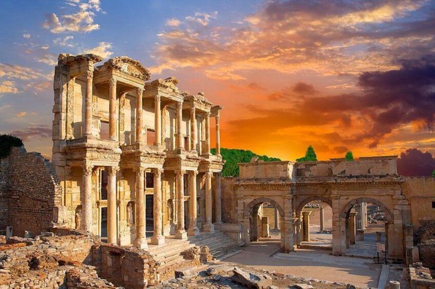 Ancient ruins with columns and arches, set against a sunset sky. 1