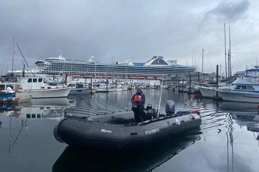 A harbor with a large cruise ship docked in the background and a small inflatable boat in the foreground. 3