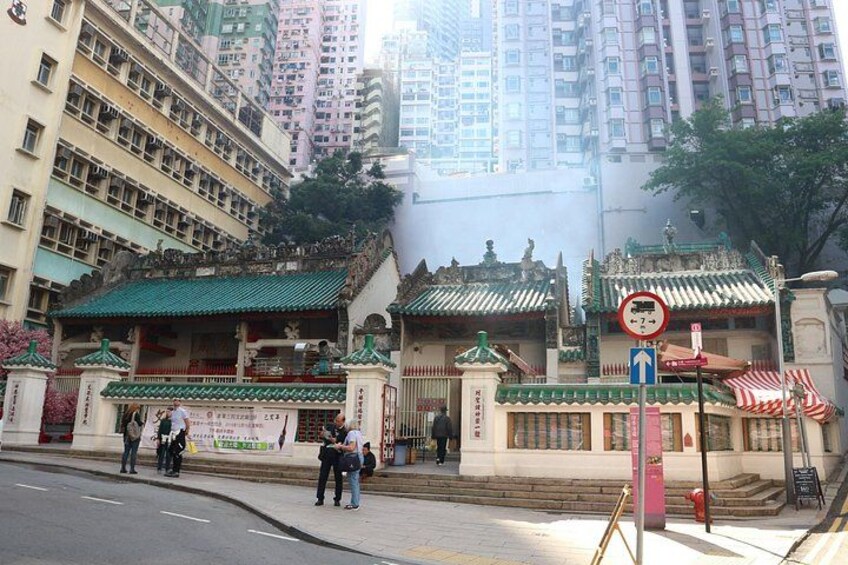A traditional Chinese gate with people standing in front, a no-parking sign, and a red fire hydrant. 3