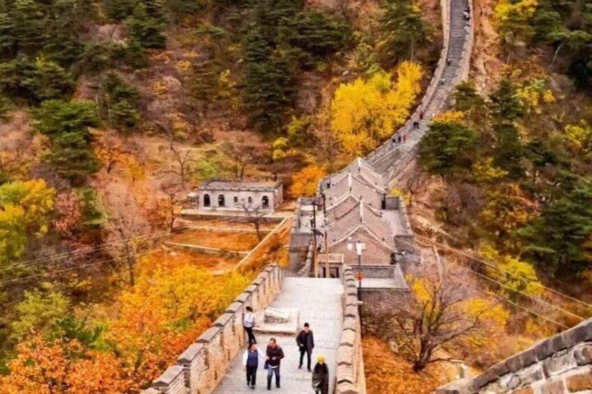 A stone bridge with people walking on it, surrounded by autumn-colored trees. 4