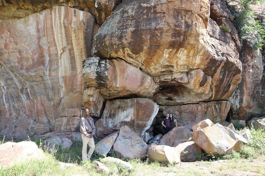 A large rock formation with a person standing in front of it. 4
