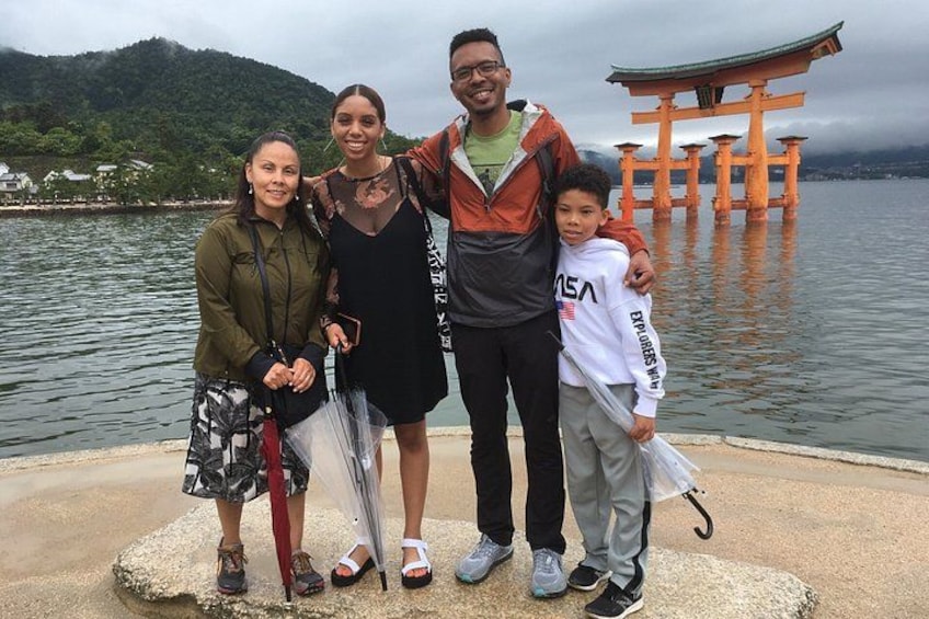 A group of people standing by a body of water with a traditional Japanese torii gate in the background. 4