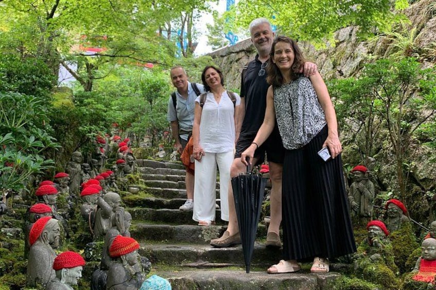 A group of people walking on stone steps surrounded by statues with red hats. 2