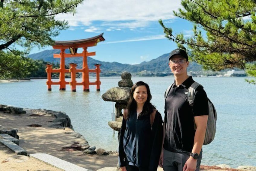 A couple standing by a traditional Japanese torii gate with a stone lantern and a scenic lake in the background. 1