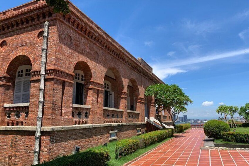 A brick building with arched windows and a paved pathway. 2