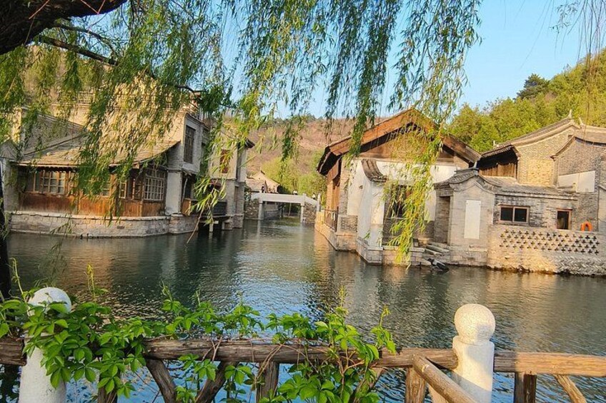 De vieilles maisons traditionnelles bordant une rivière paisible, des ponts en bois et une végétation luxuriante. 5