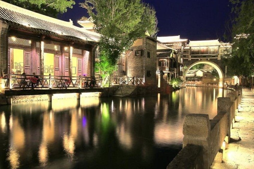 Un patio chinois traditionnel, agrémenté d’un canal, de ponts en bois et de bâtiments illuminés la nuit. 1
