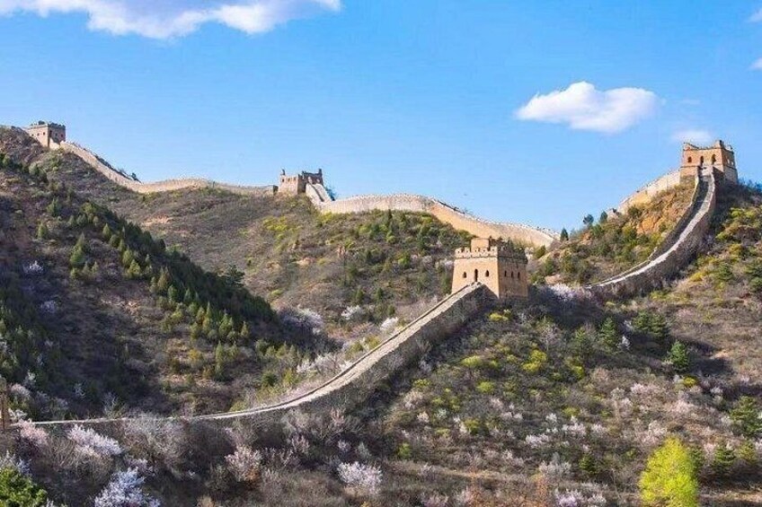 The Great Wall of China, a long winding structure, with watchtowers and towers, set against a hilly landscape with sparse vegetation. 3