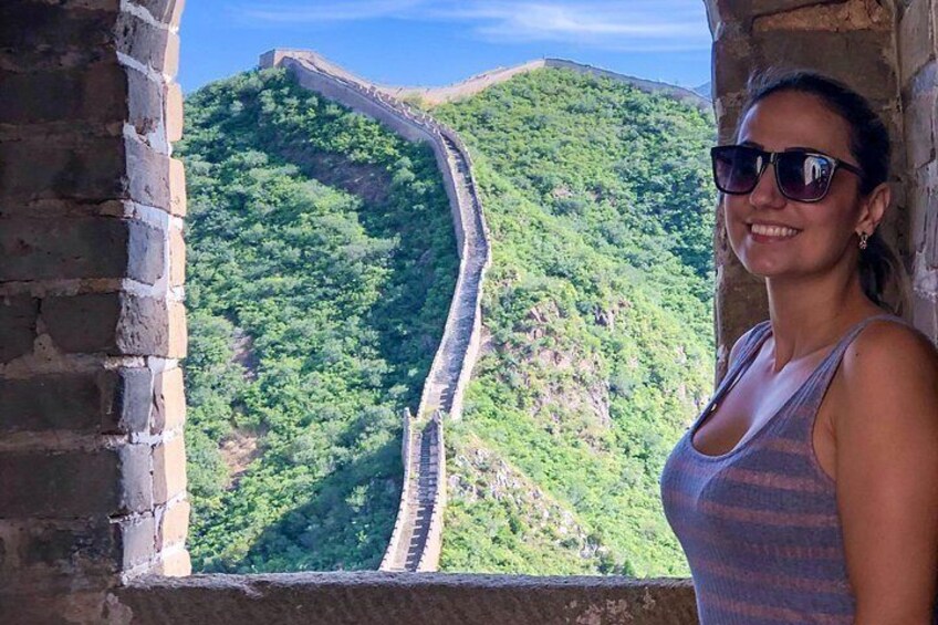 A person standing by a window overlooking a mountainous landscape with a long, winding road. 5