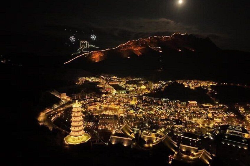 A night view of a city with illuminated buildings, a prominent pagoda, and a mountain in the background. 1