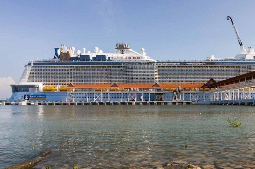 A large cruise ship docked at a pier with clear water in the foreground. 1
