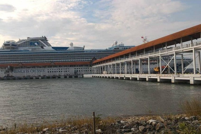 A large cruise ship docked at a port with a covered walkway. 3