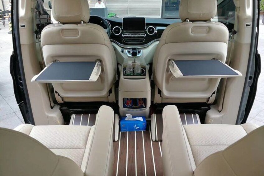 A vehicle interior with two seats, a center console, and a rear storage compartment. 2