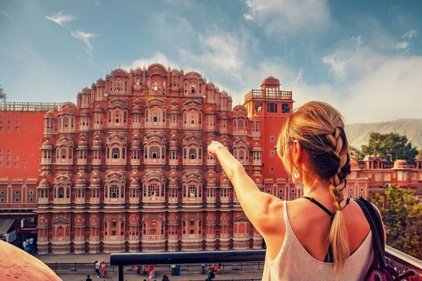 A person with a braided hairstyle looking at a large, ornate building with multiple arches and domes. 2