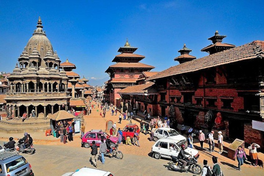 A bustling street with traditional architecture, including tiered temples and a prominent stupa. 4