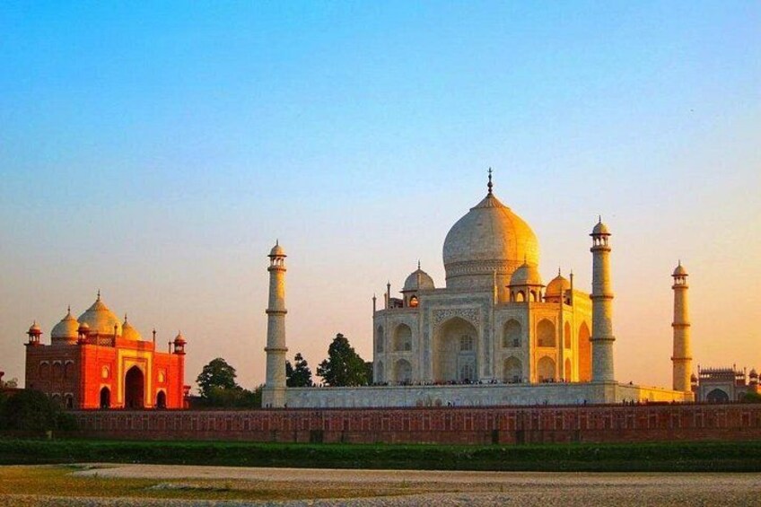 Taj Mahal, med sina fyra minareter och stora kupol, omgiven av en röd mur. 1
