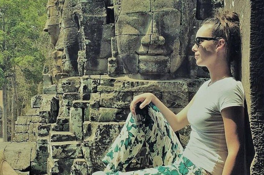 Happy client at Bayon temple with smiling buddha faces in background 2