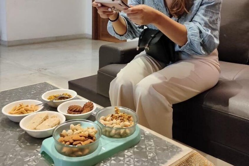 Una persona sentada en un sofá con cuencos de frutos secos y aperitivos sobre una mesa. 3