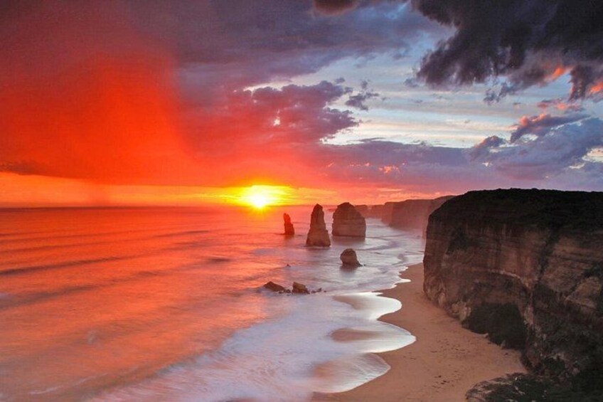 A sunset over a beach with rock formations. 1
