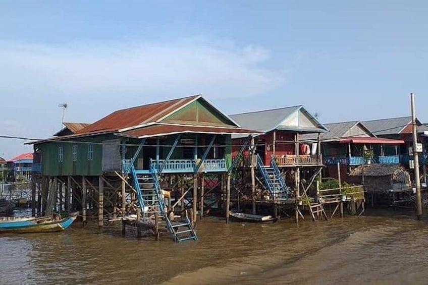 A waterfront community with stilt houses, boats, and a clear sky. 4