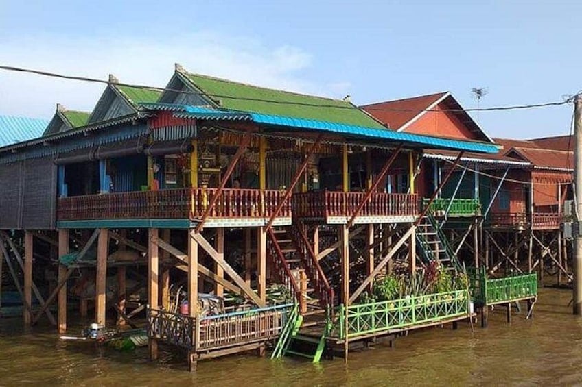 A stilt house with a green roof, wooden structure, and a small balcony. 3
