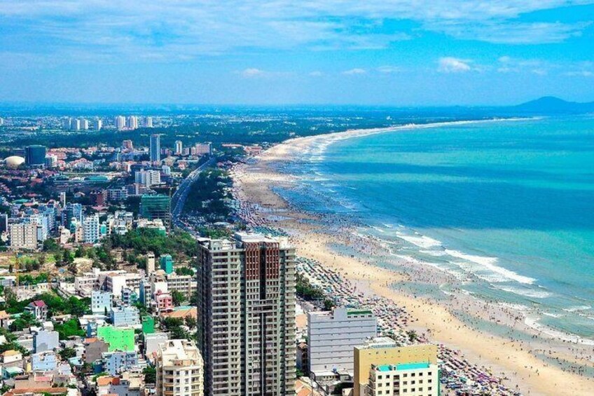 A coastal cityscape with a beach, high-rise buildings, and a clear sky. 3