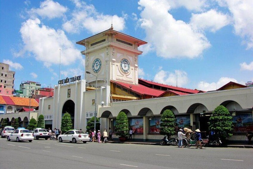 A clock tower, a market area, and a busy street with pedestrians and vehicles. 1