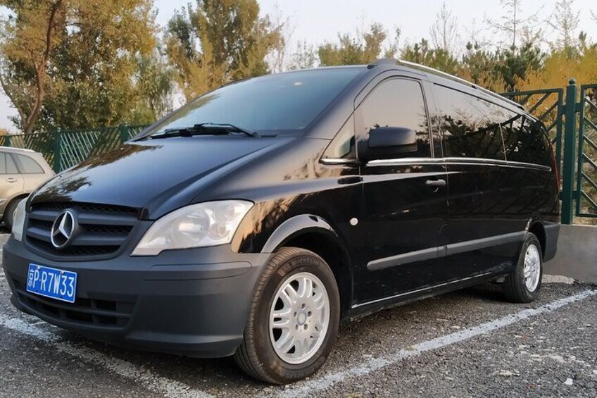 A black Mercedes van parked on a gravel surface with a license plate visible. 3