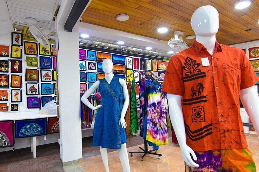 A clothing store with mannequins displaying dresses and a colorful wall of artwork. 1