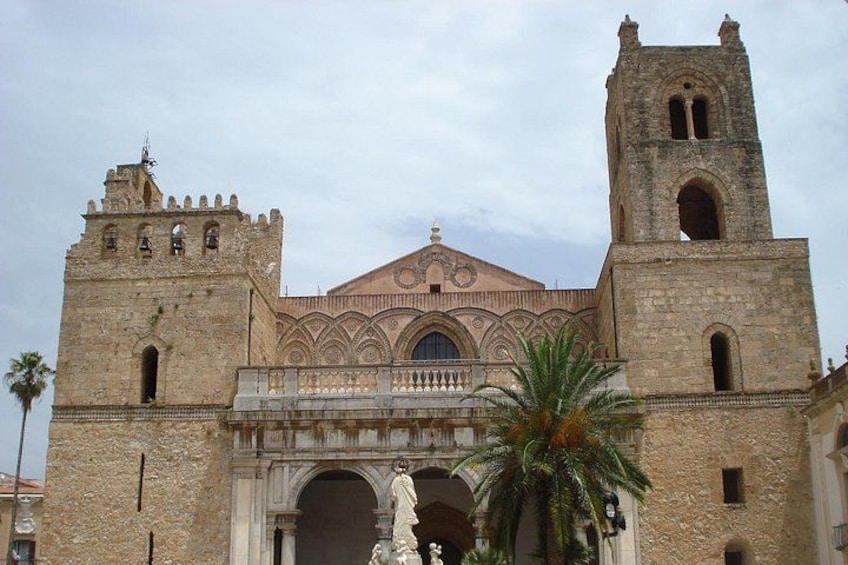 A historic building with two towers, a central dome, and a statue in front. 2