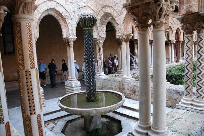 An ancient courtyard with columns, arches, and a central fountain. 4