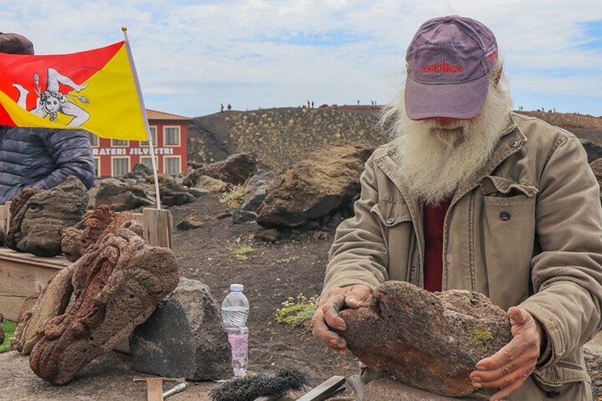 Una persona sosteniendo una roca grande, con una bandera y una botella cerca. 2