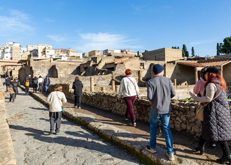 Un grupo de personas caminando por una calle adoquinada en un pueblo antiguo con edificios históricos de piedra. 5