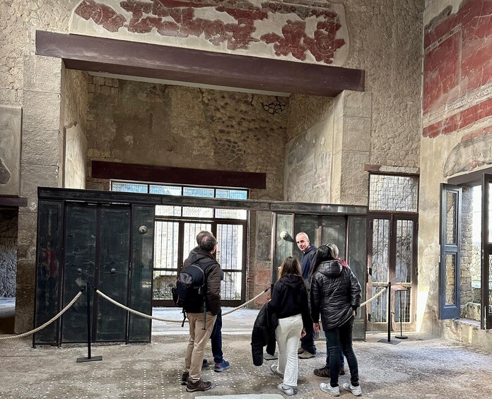 Un grupo de personas de pie en un edificio histórico con paredes de piedra y suelo de baldosas. 2