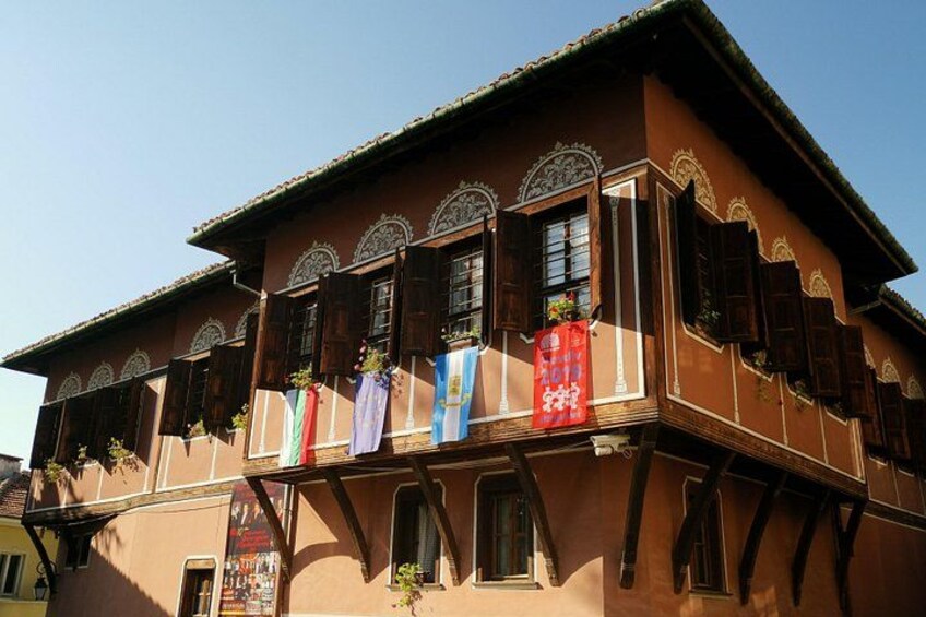 A traditional building with wooden shutters and balconies, adorned with colorful flags. 5