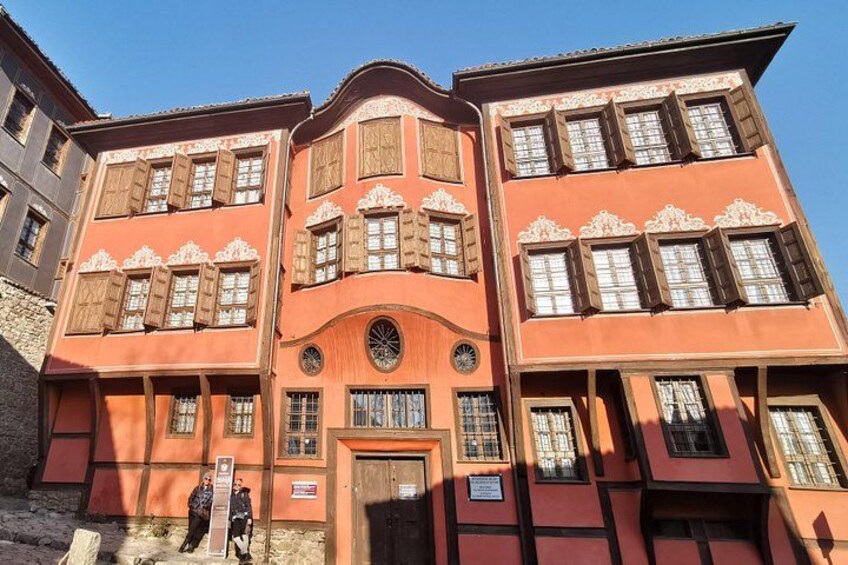 A multi-story building with ornate wooden shutters and a central circular window. 2
