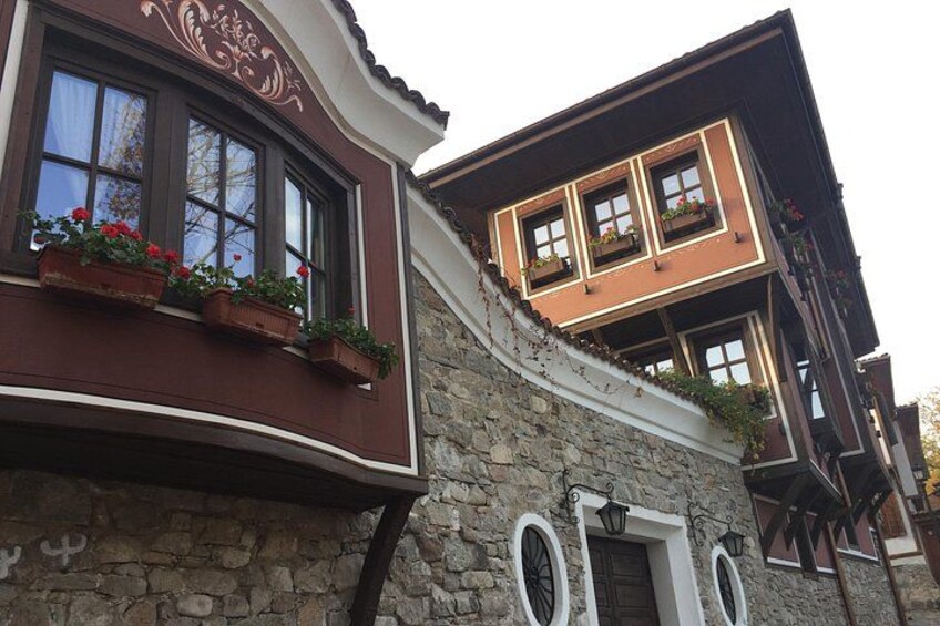 Un bâtiment à la façade en pierre, aux encadrements de fenêtres en bois et agrémenté de jardinières. 1