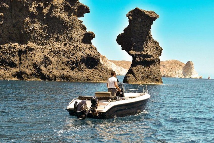 A boat on calm water with a rocky coastline in the background. 5