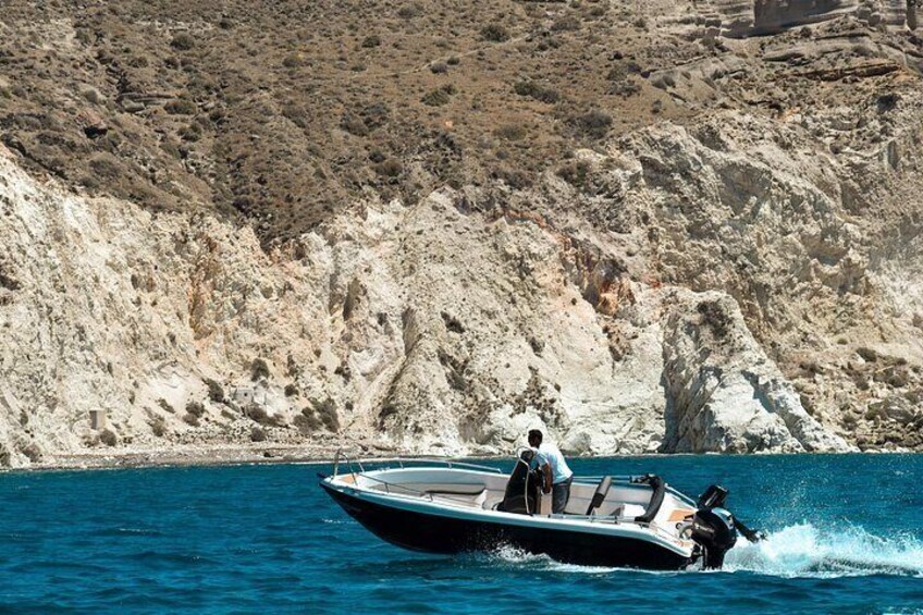 A motorboat on a calm sea with a rocky coastline in the background. 2