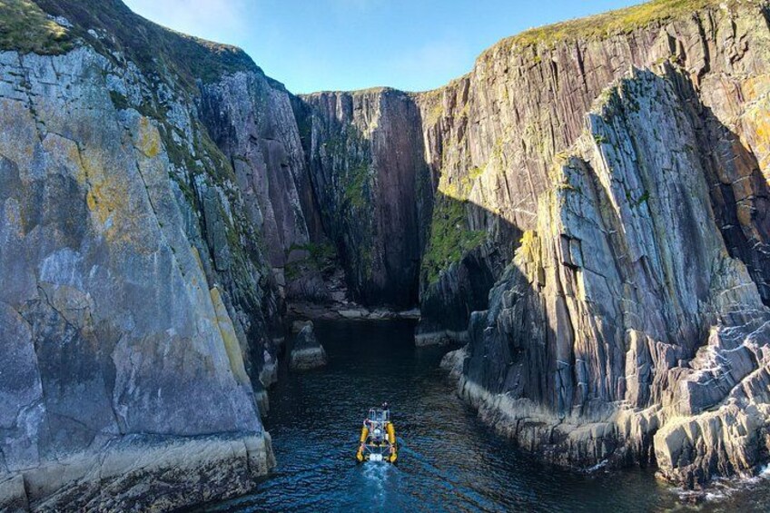 A narrow canyon with steep rock walls and a small boat navigating through the water. 2