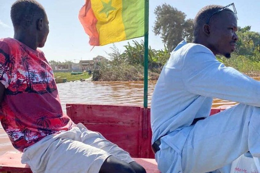 Dos personas sentadas en un bote, con una bandera al fondo. 4