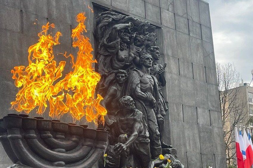 A statue with flames, a flag, and a building. 1