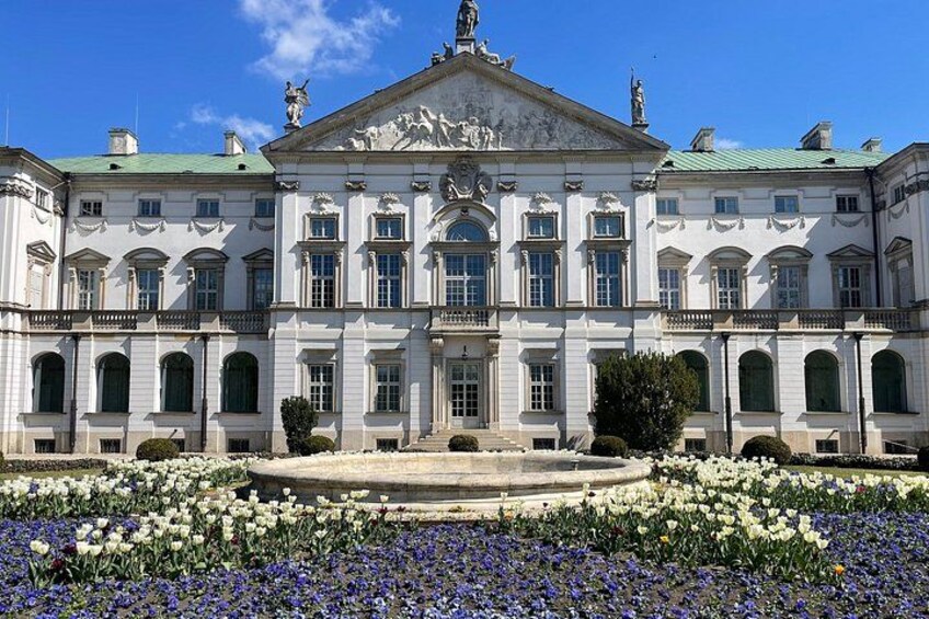 A large classical building with a central courtyard, surrounded by a variety of flowers. 3