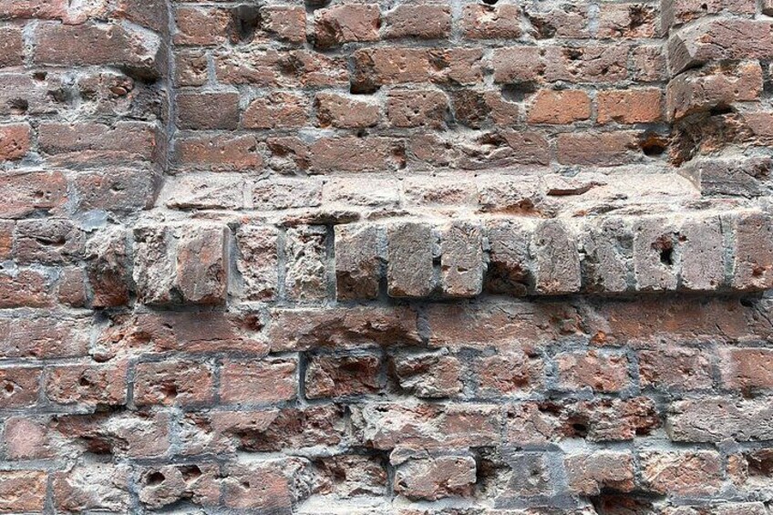 A weathered brick wall with visible mortar and some bricks missing. 2