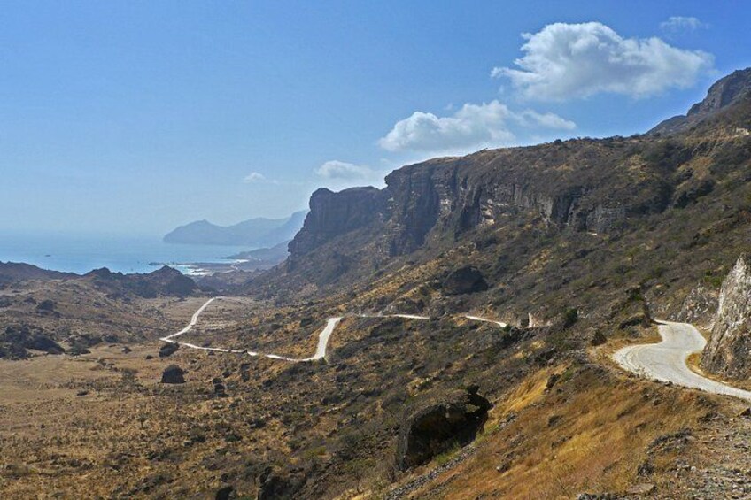 Un camino sinuoso de montaña, terreno rocoso y la costa a lo lejos. 3