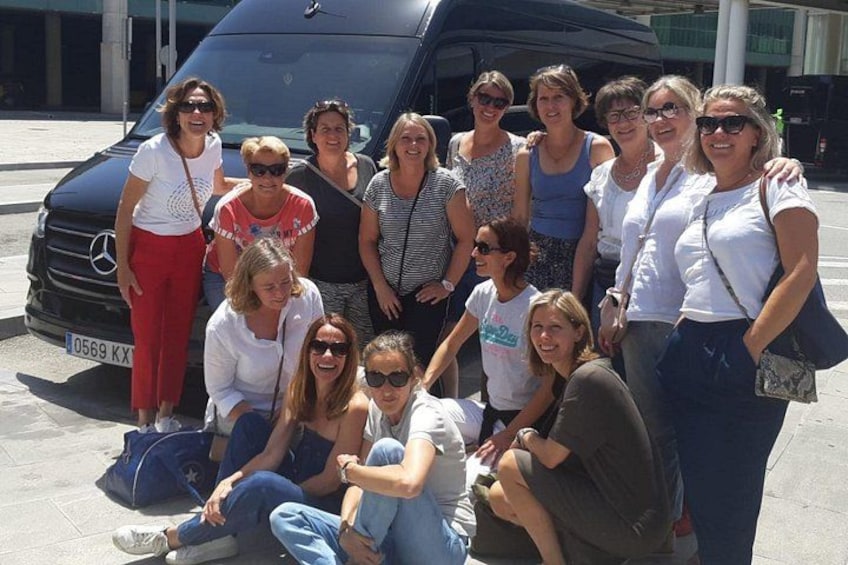 A group of people posing in front of a black vehicle with a license plate. 3