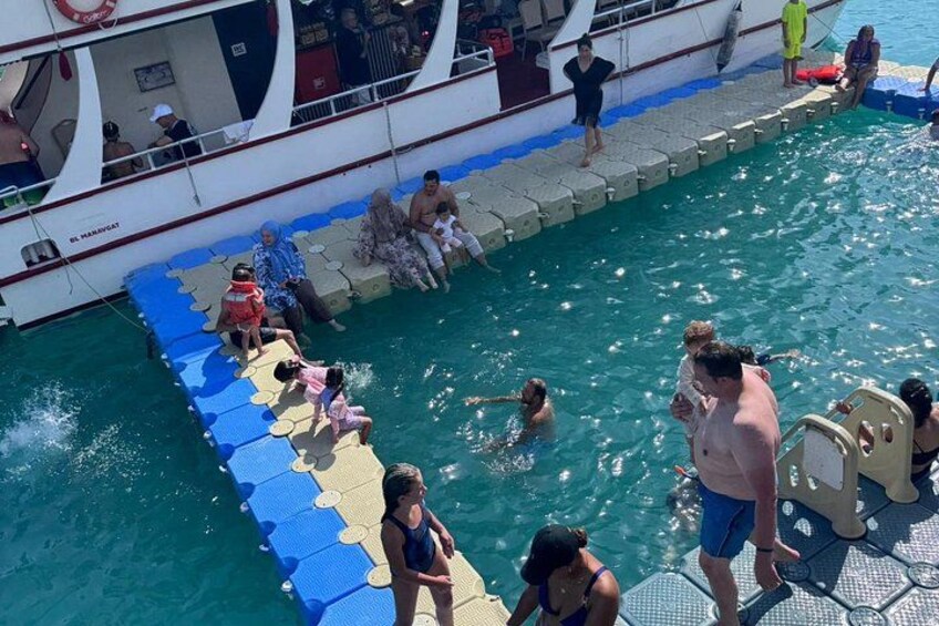 A swimming pool with people swimming and standing on the deck. 2