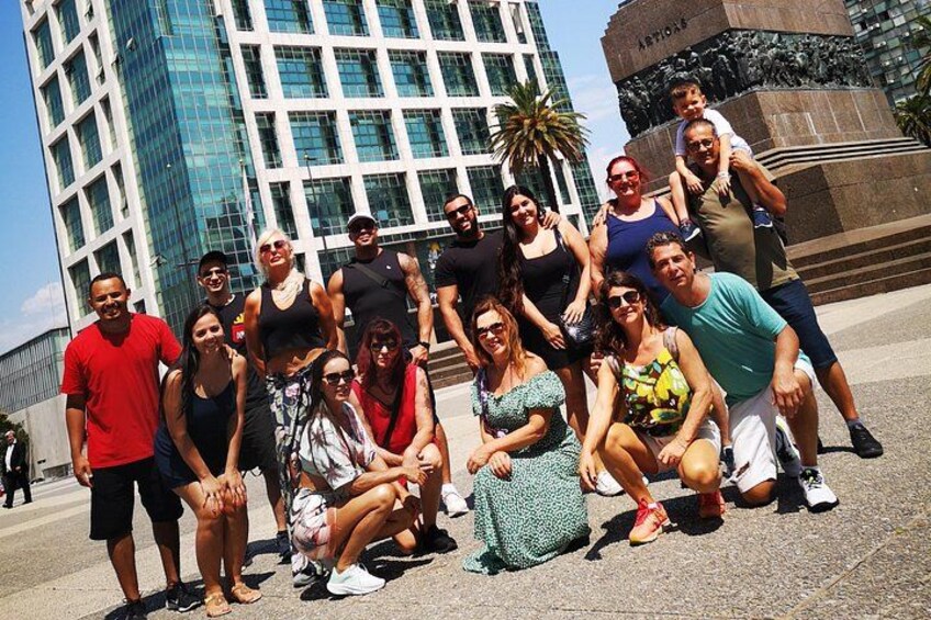 Un grupo de personas posando frente a un edificio moderno y un monumento. 2