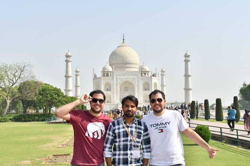 Drei Personen stehen vor dem Taj Mahal. 1
