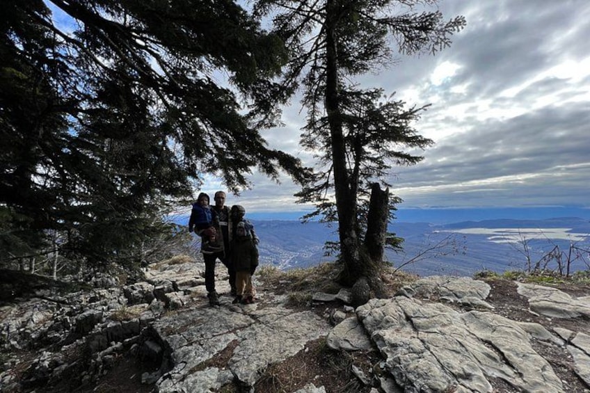 A group of people standing on rocky terrain with a view of a lake and mountains in the distance. 3
